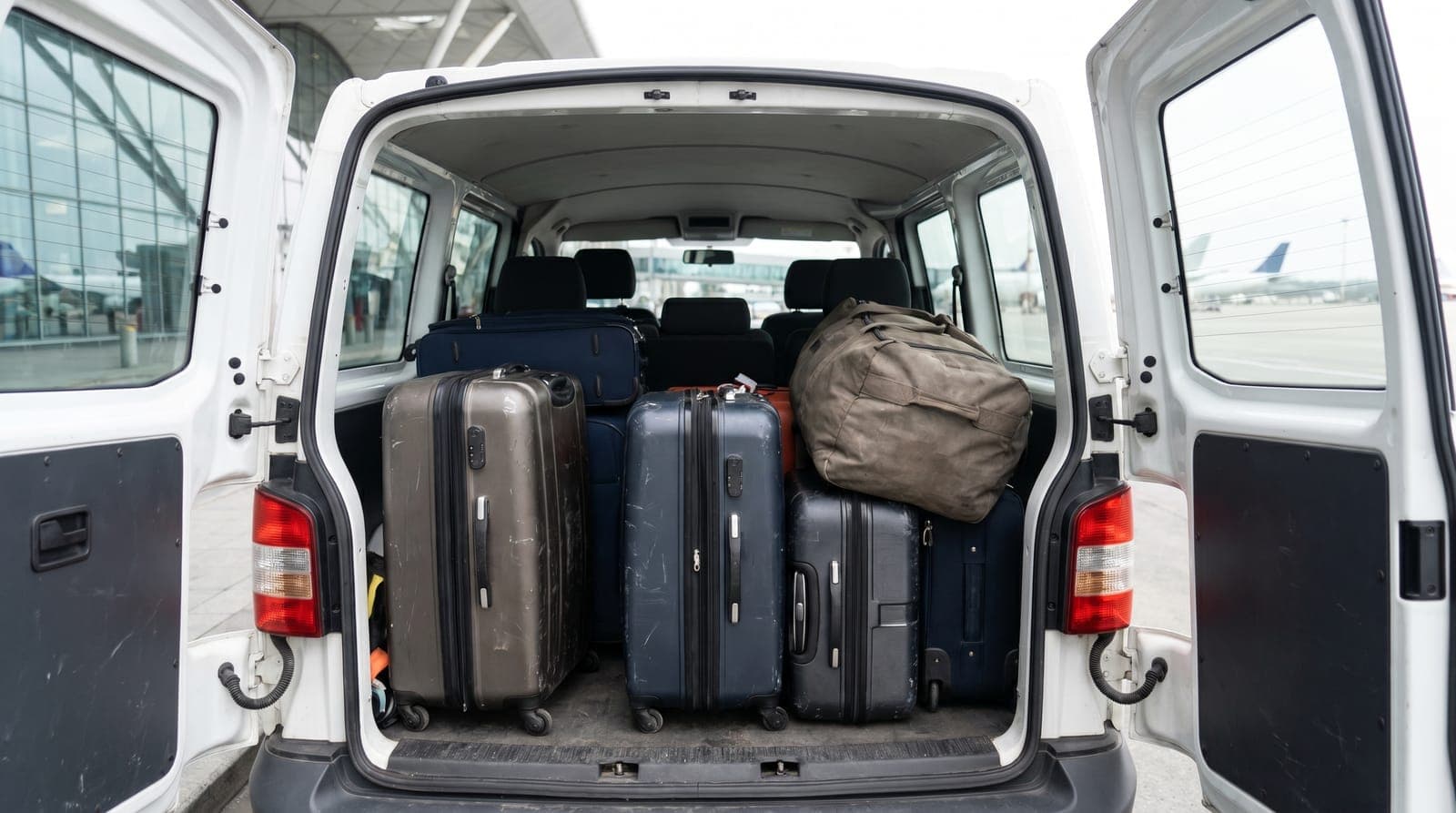 Maletas grandes cargadas en la parte trasera de una furgoneta camino del aeropuerto